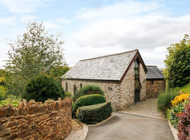 A stone building with a pitched roof surrounded by trees and bushes at Frogwell Chapel in Frogwell near Callington