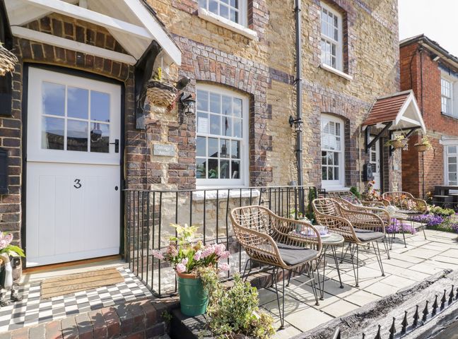Front entrance of a stone cottage with a white door numbered 3 and outdoor seating at 3 Canalside Cottages Stoke Bruerne near Roade