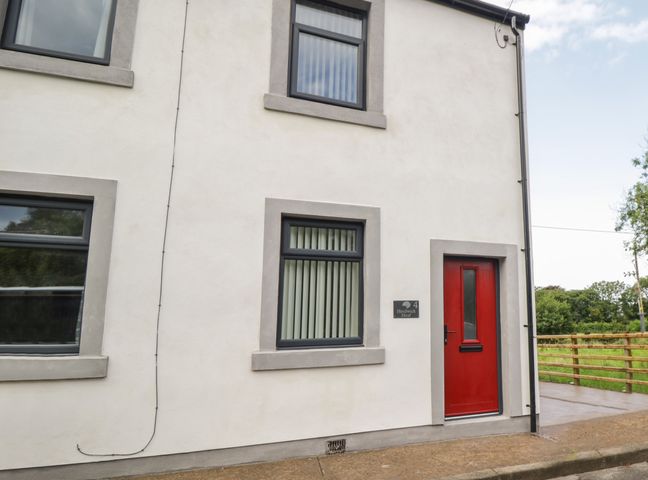 Exterior view of a white house with three windows and a red door at Herdwick Heaf in Ennerdale