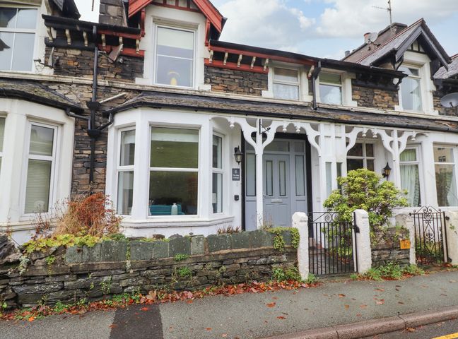 Stone and white terraced house with bay windows and a small front garden at The Bay Cottage in Ambleside
