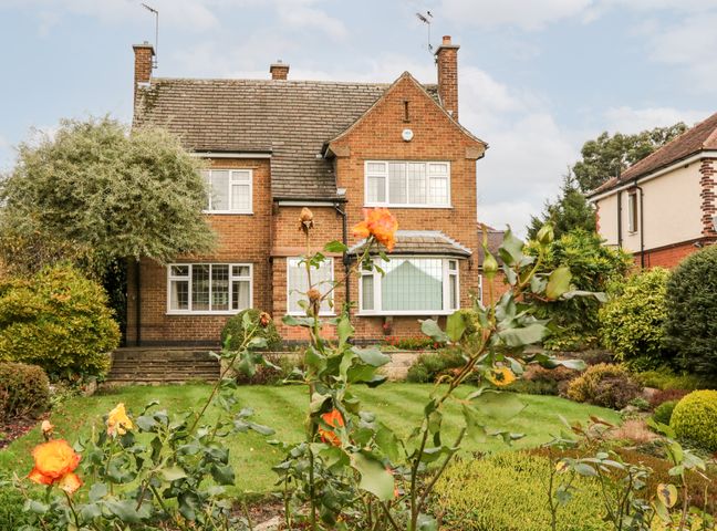 A brick house with a tiled roof and white framed windows with a garden and orange flowers in the foreground at Field House in Swanwick