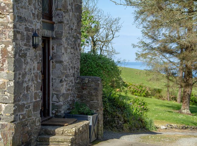 A stone entrance with a door and light fixture at Carrows Stable Morwenstow