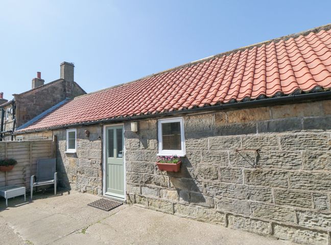 Stone cottage with a red tiled roof door and windows with flower boxes and outdoor chairs at Abbey View Cottage High Normanby near Robin Hood's Bay