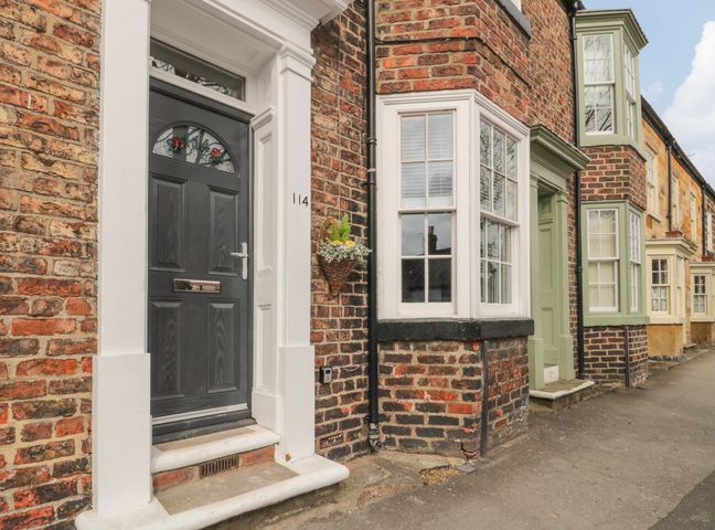 A row of brick houses with bay windows and front doors on a sidewalk at Westgate in Guisborough