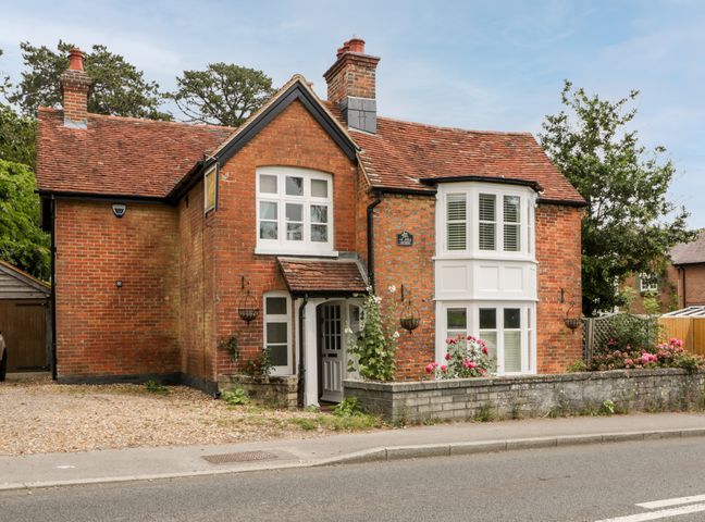 A brick house with white windows and a tiled roof by a roadside at Oakapple Cottage in Swan Green near Lyndhurst