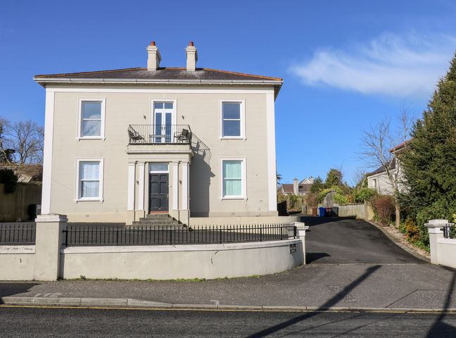 A large two-story house with a black front door and balcony above it at Beachcomber in Ballycastle