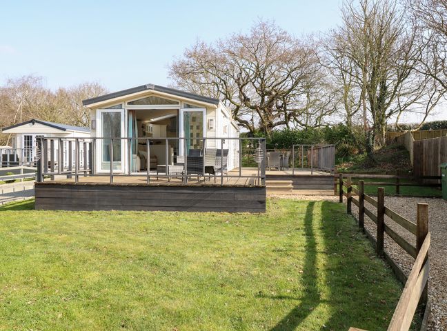 A mobile home with an outdoor deck and chairs in a grassy area at 109 Pentney Lakes in Pentney near Kings Lynn