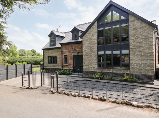 Front view of a modern house with large windows and a metal gate at Thornbury in Barnard's Green Malvern