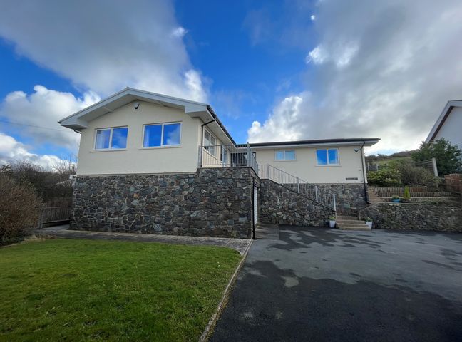 A house with stone and white exterior walls a driveway and grass lawn at Aelwyd Y Don in Tresaith