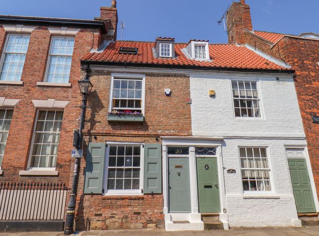 A street view of connected brick and white painted houses with red tiled roofs and green doors at Bobbies' Retreat 20 High Street Bridlington
