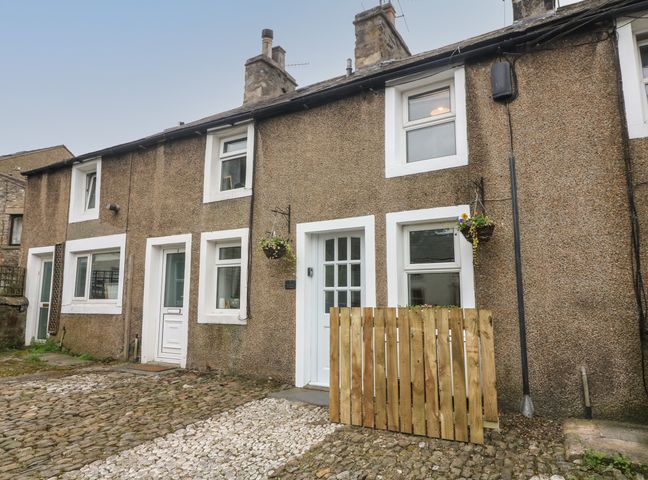 Row of stone cottages with white doors and windows on a cobblestone street at Honey Pot Cottage in High Bentham