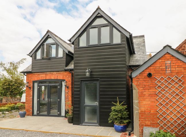 Exterior view of a brick and black cladded house with large windows and potted plants at Hill Coach House in Watchet