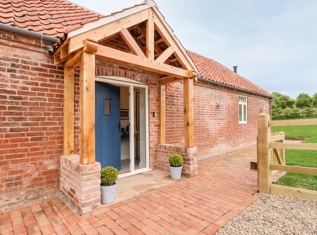 A brick house entrance with a blue door and wooden porch at Carvers Rest in Southwell