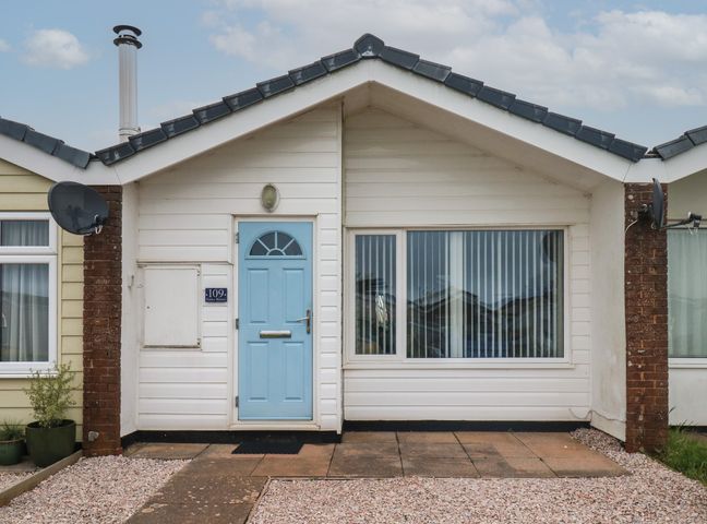 Front of a single-story house with a blue door and large window at Sunny Breeze in Malborough