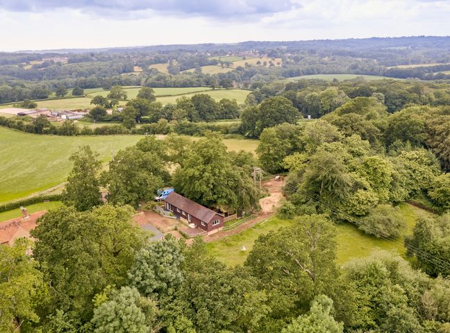 A rural farm area with trees fields and farm buildings at Forest Farm Cottage in Balcombe