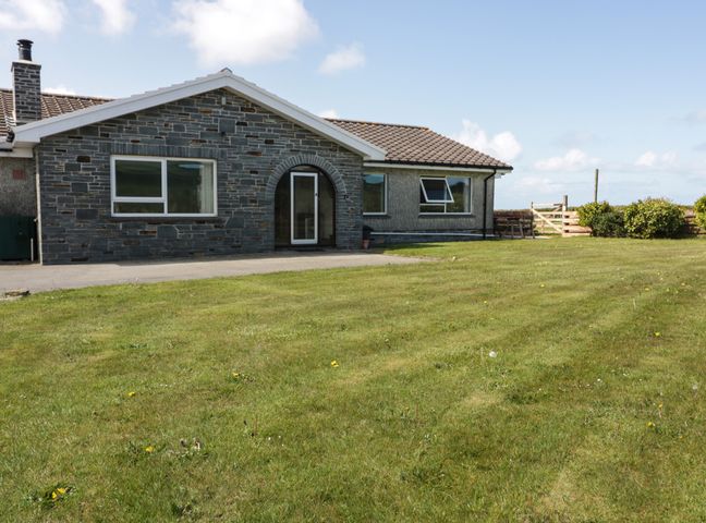A single-story house with stone and stucco exterior walls fronted by a lawn at Boscastle View in Boscastle