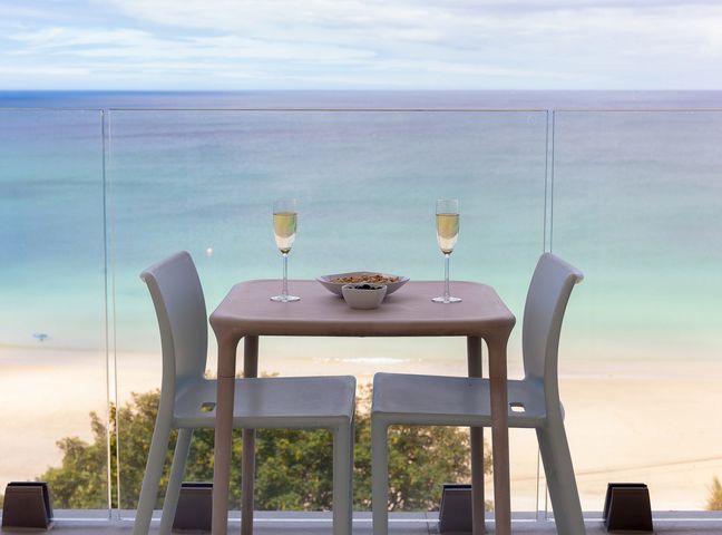 A small table with two chairs and two glasses of wine overlooking a beach and ocean at Aquamarine Carbis Bay