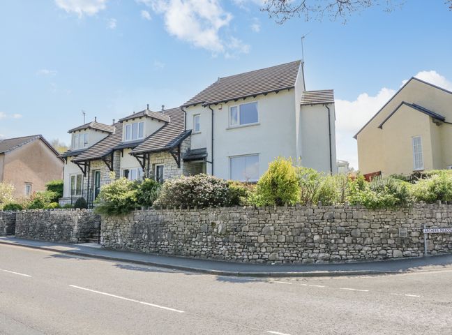 A row of houses with tiled roofs and stone walls surrounded by bushes and plants at Viewpoint in Kendal