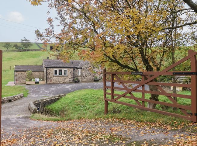 A cottage with a stone exterior and gate at Beckside Cottage in Cowling near Skipton