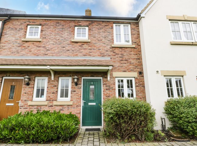 Exterior of a brick townhouse with green door number 4 and bushes in front at Puffin Cottage The Bay Filey