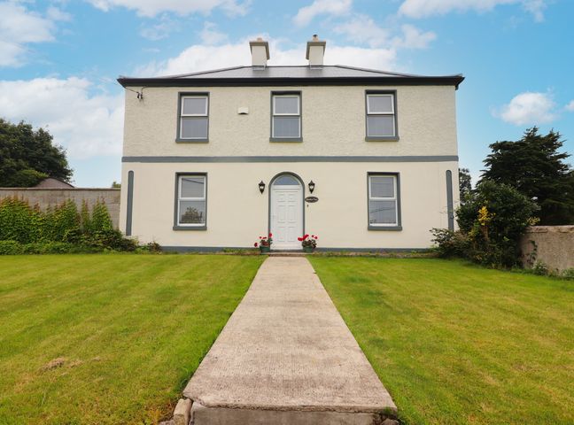 A two-story house with a front lawn and a concrete pathway leading to the front door at Meadow View in Quin County Clare