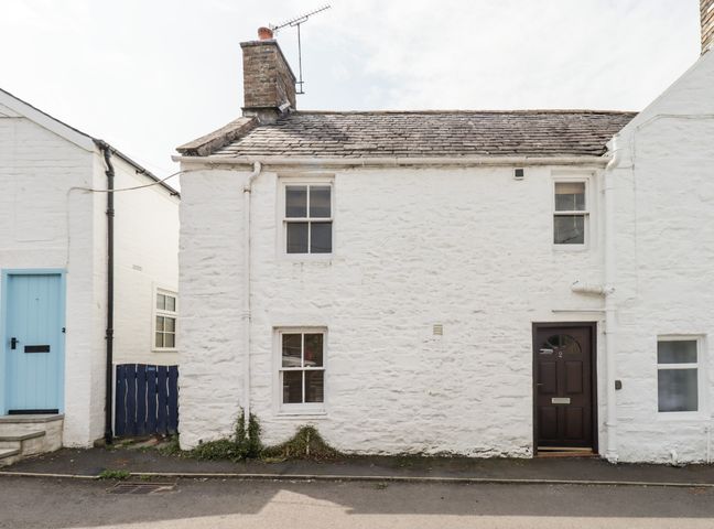 A white stone house with a black door and three windows on a street at 2 Burnside Place Kirkcudbright