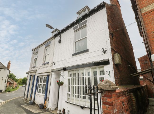 A white two-story building with multiple windows and a street lamp on a corner at The Pebbles in Hornsea