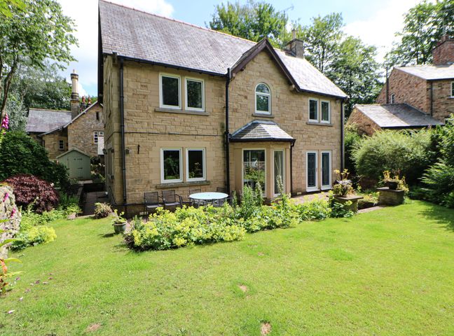 A stone house with multiple windows and a garden with plants and outdoor furniture at Bridgedown House in Richmond