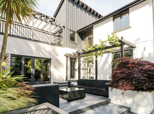 An outdoor patio with black wicker furniture and plants at Iroko in Millbrook