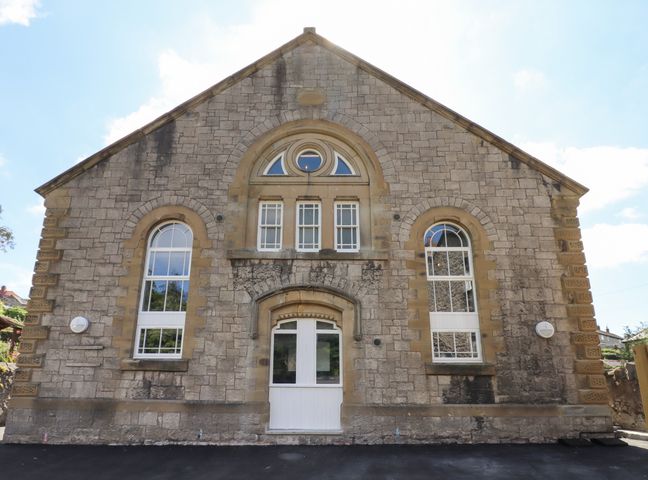 A stone building facade with arched windows and a white door at The Sigma Penthouse in Dyserth