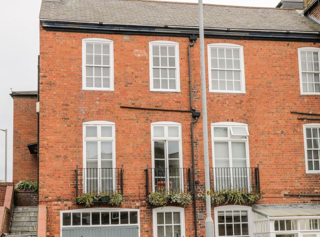A brick building with multiple white windows and flower boxes attached to black railings at 7a Belvoir Terrace in Scarborough