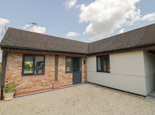 An exterior view of a single story house with a gravel driveway and a wooden door at Garden Cottage in Upton Upon Severn