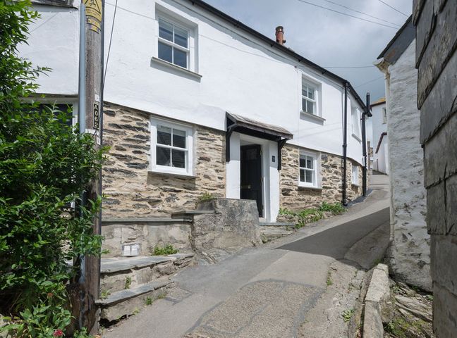A narrow street with a stone and white cottage with windows and a black door Bre Cottage Port Isaac