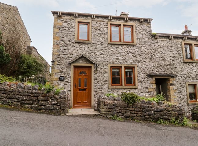 Stone house with wooden door and windows and small garden walls at Top House in Settle