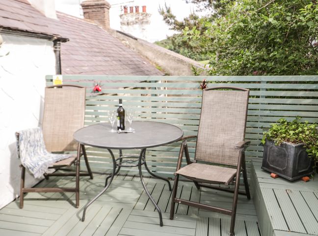 An outdoor seating area with two chairs and a round metal table with a bottle and glasses at 7 Watkin Street in Conwy