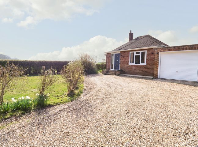 A brick bungalow with a gravel driveway and a garage surrounded by grass and bushes at Woodview in Roughton