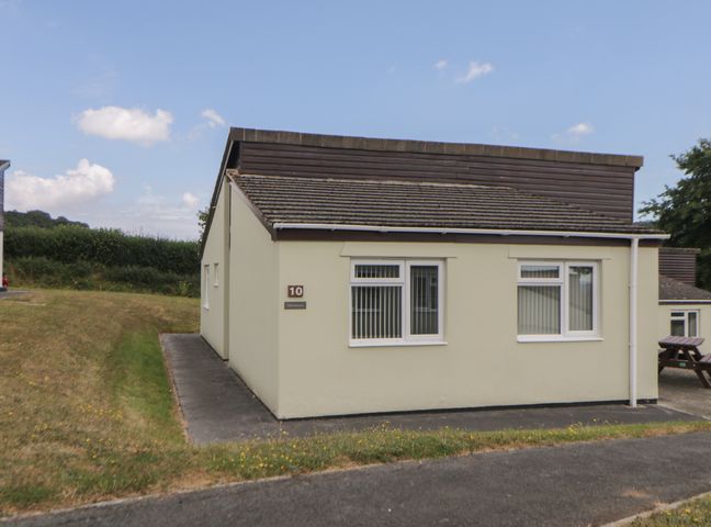 A single story beige bungalow with windows and a small path at Harcombe House Bungalow 10 Chudleigh