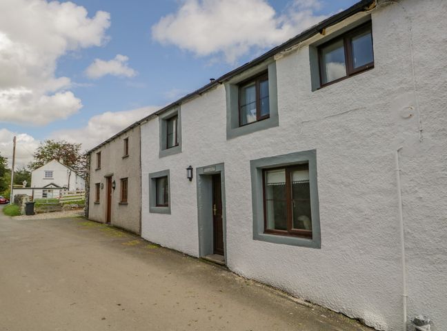 A row of white and beige cottages on a street with windows and doors at Ashness in Bassenthwaite near Keswick