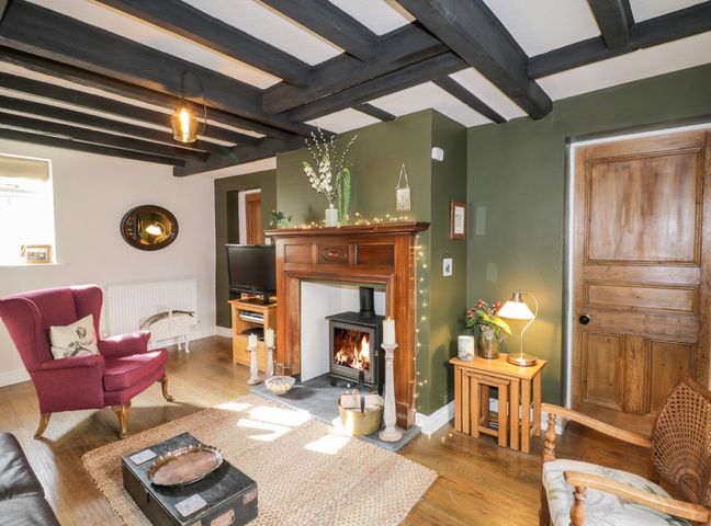 A living room with a fireplace red armchair and wooden furniture at The Nook in Whitby