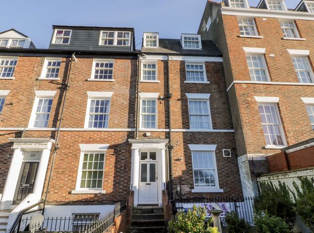 A brick townhouse with white framed windows and a white door with steps leading up to it at Highview in Scarborough