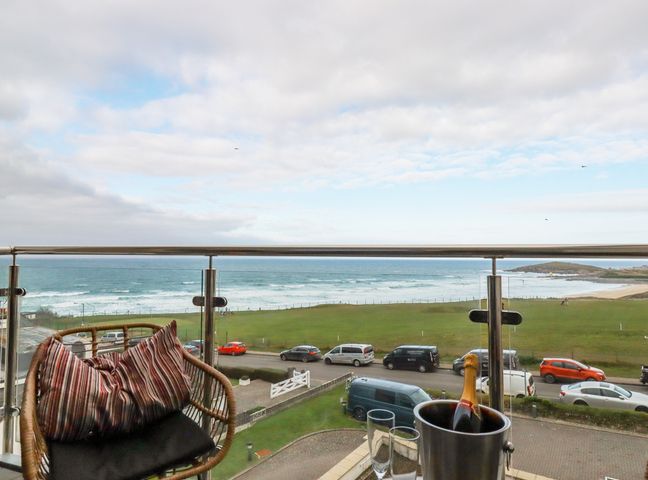A balcony with a chair and a bottle of champagne in an ice bucket overlooking the ocean at Fistral Retreat in Newquay