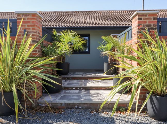 An outdoor entrance area with steps and potted plants between brick pillars at Chalet 1 in Sherburn