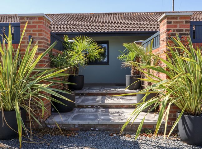An entrance with steps leading to a door flanked by brick pillars and potted plants at Chalet 2 East Heslerton near Sherburn