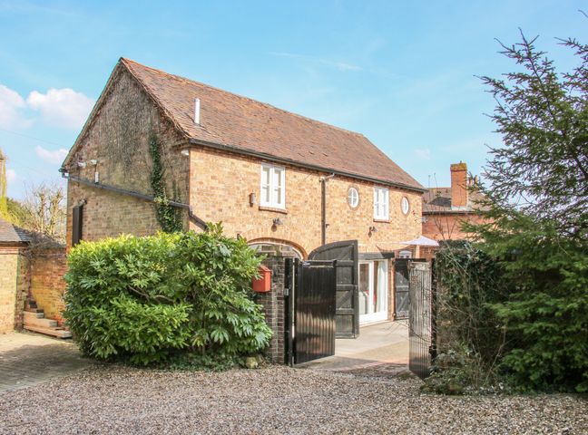 A brick house with black gates and shrubbery at Coach House at Old Vicarage in Madeley