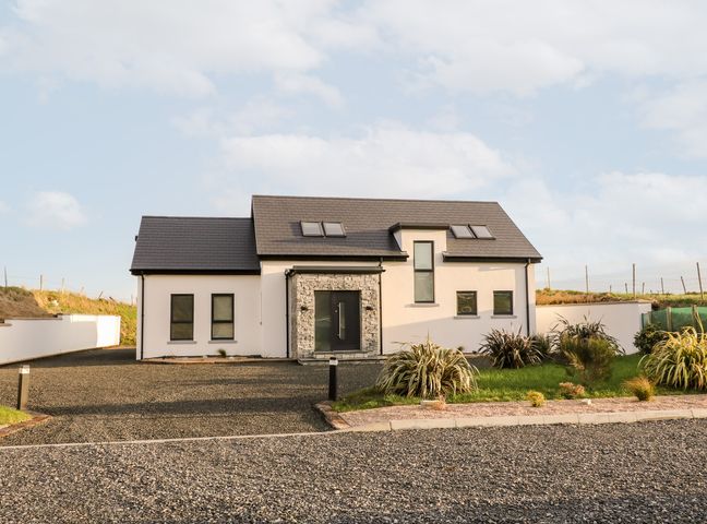 A detached house with a dark roof two skylights and a stone framed front door at The Beachhouse in Meenlaragh near Gortahork County Donegal