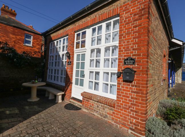 A brick house exterior with white framed windows a door a mailbox and a small outdoor table with a bench at Goliath in Brewers Quay Harbour