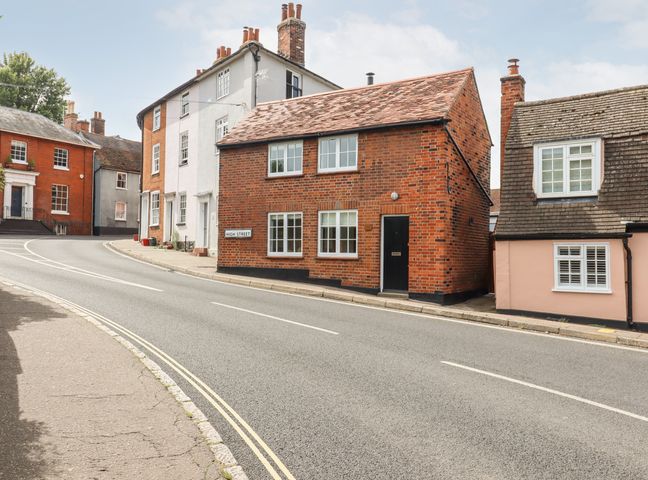 A street with brick and plaster houses and a road sign reading high street at Wherry Cottage in Manningtree