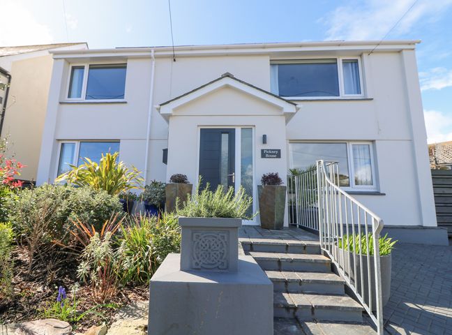 Exterior view of a two story house with a front entrance door stairs and plants at Pickney House Killigarth near Polperro
