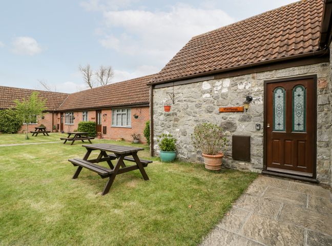A courtyard with picnic tables and stone and brick buildings at Carthouse in Brean