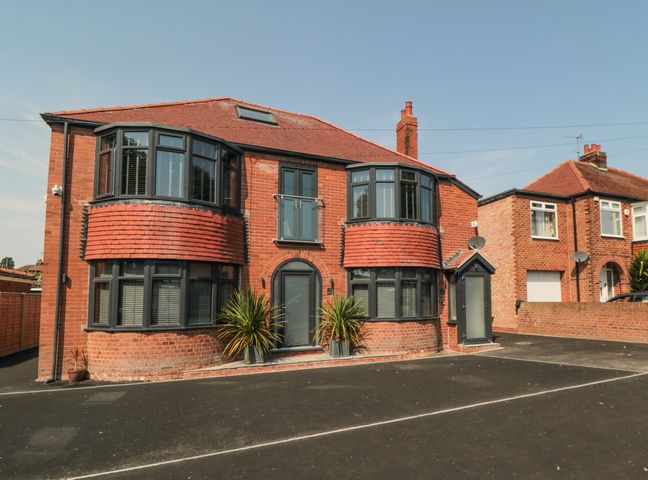 A brick detached house with bay windows and a paved driveway at Nightingales in Bridlington